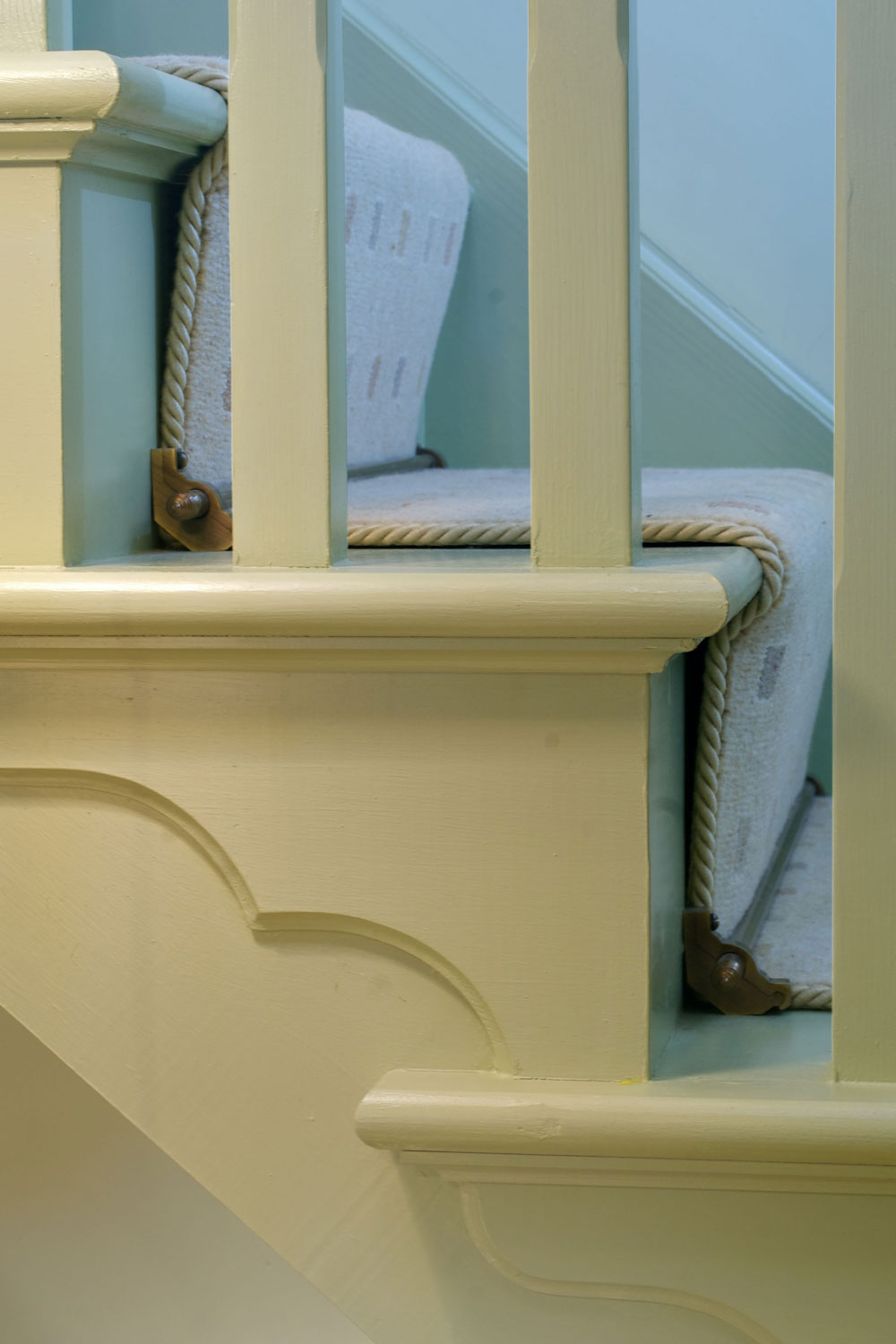 Cream stair runner edged in carpet tape on cream stairs showing through spindels