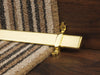 Vue stair rods in polished brass on striped carpet