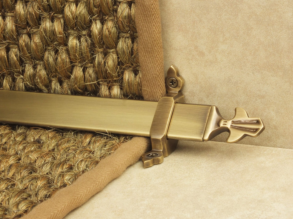 Louis design of stair rod with fleur-de-lys end, antique brass on red carpet